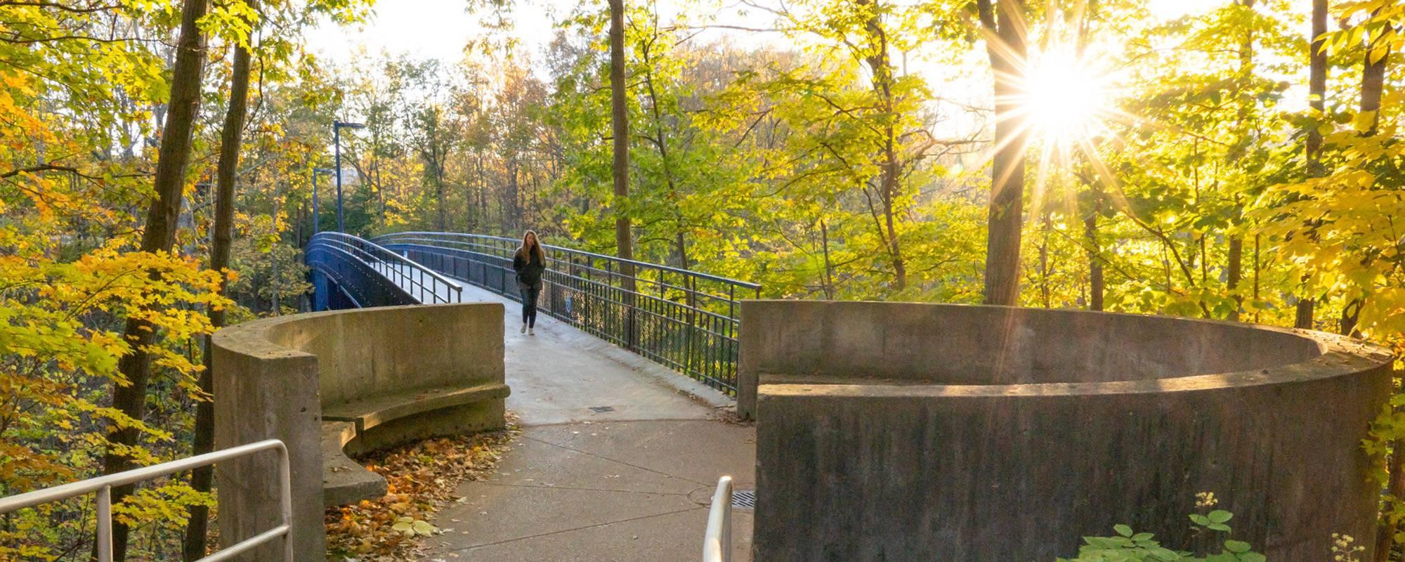 Student finding her way across the Little Mac Bridge on Grand Valley campus.